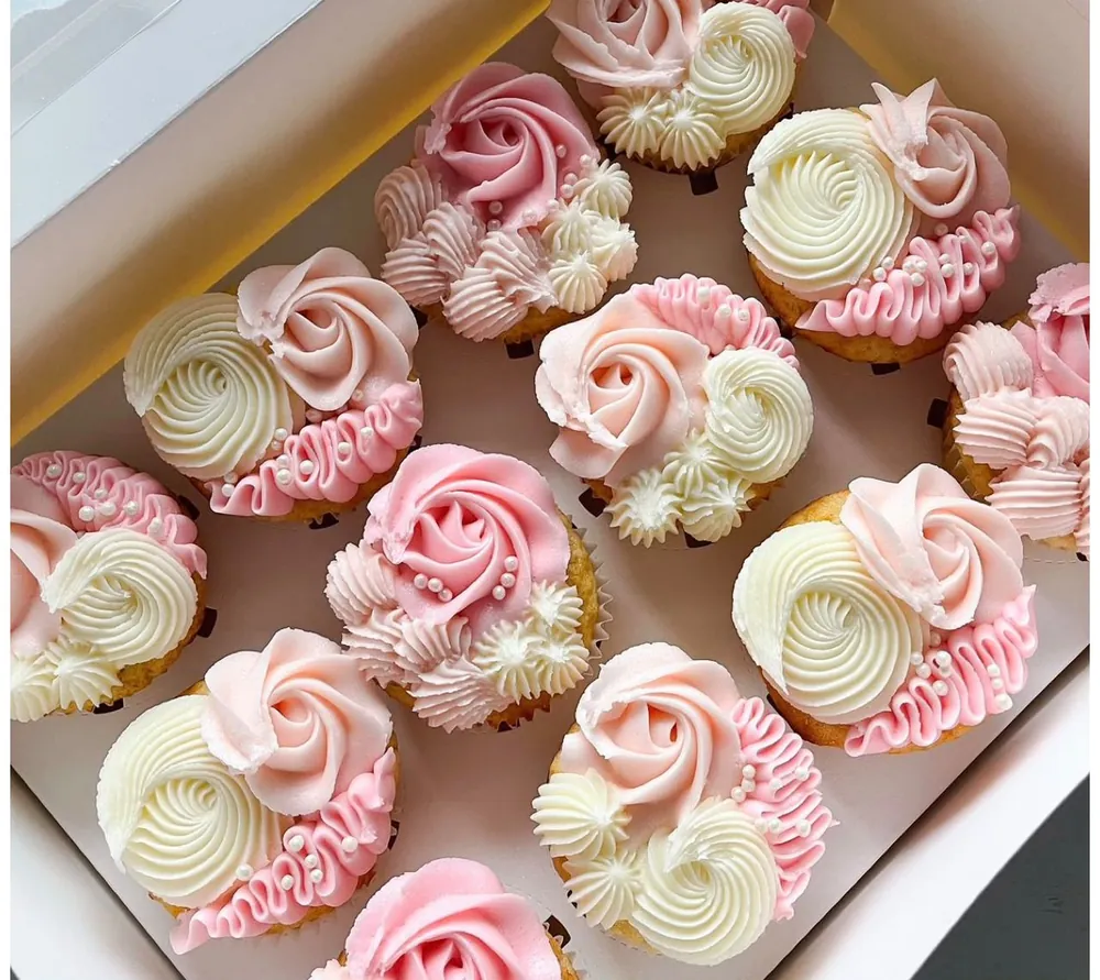 Caja de cupcakes con rosas de crema en tonos rosados